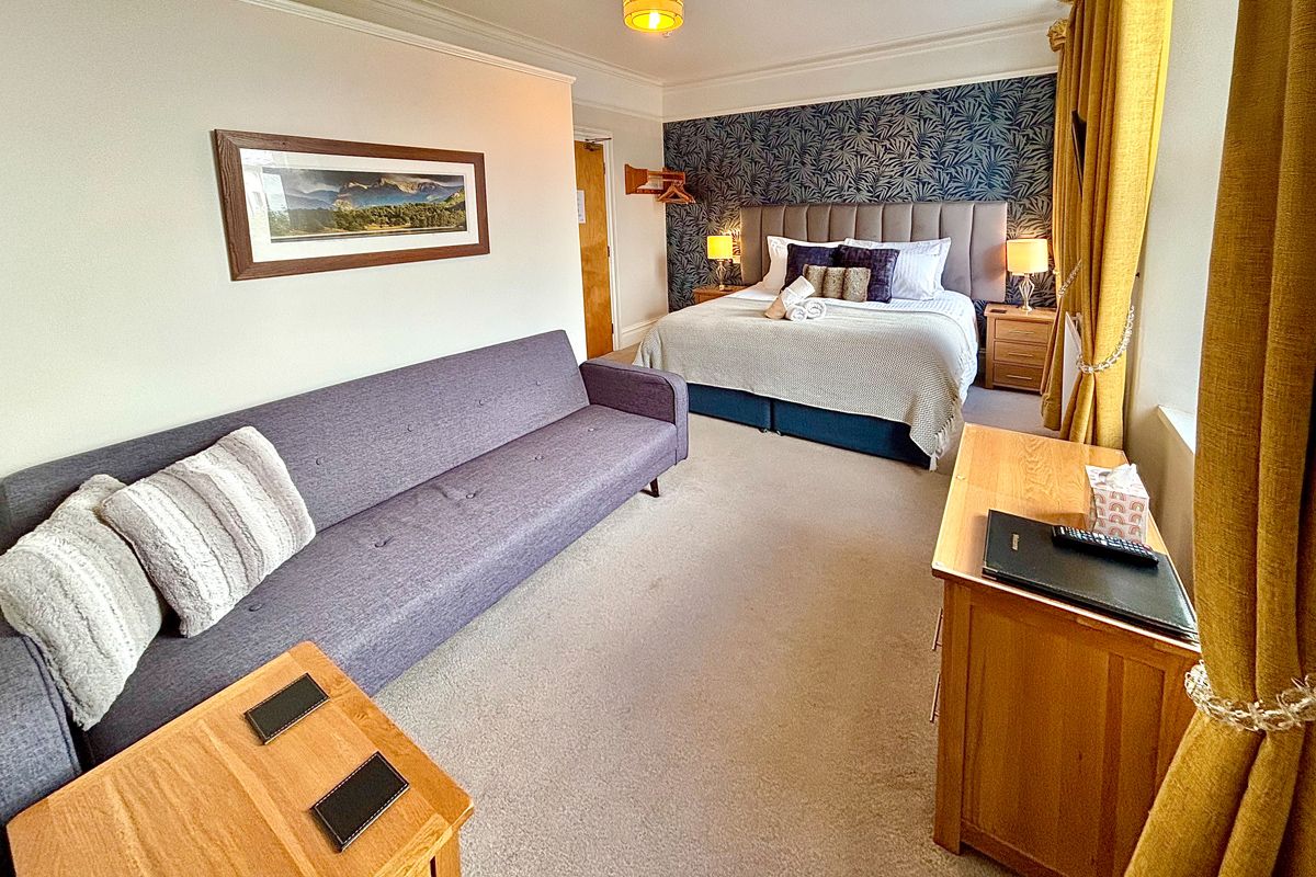 Room 2 – Large double room with sofa seating and warm, modern décor.