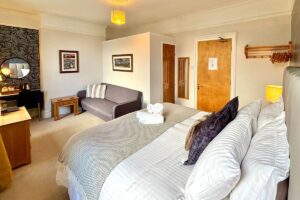 Room 2 – Bright double setup with super-kingsize bed and soft furnishings.