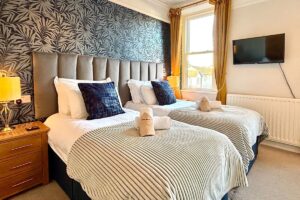 Room 2 – Spacious twin setup with sofa seating and plenty of natural light.